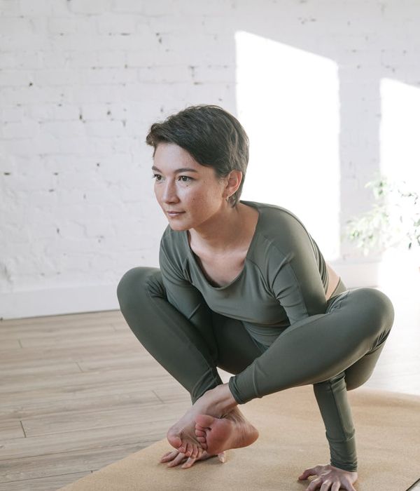 Woman in a graceful yoga pose in a bright, serene room.